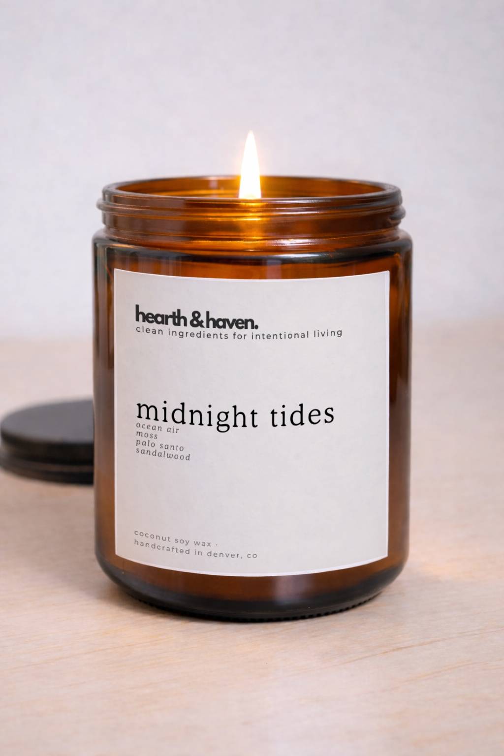 hearth & haven Midnight Tides candle burning in amber glass jar, phthalate-free fragrance with ocean air, moss, palo santo and sandalwood, handcrafted in Denver CO