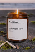 Hearth & Haven candle labeled 'midnight tides' on a dark surface with natural elements.
