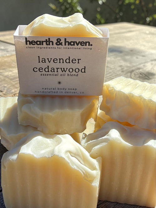 Hearth & Haven lavender cedarwood natural bar soap bars stacked on rustic wood in sunlight

